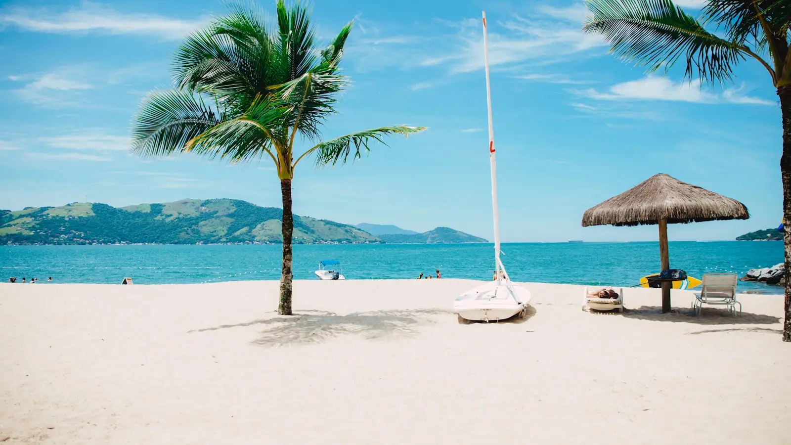 Children playing in shallow calm water on a gently shelving south Maui beach with palms and a lifeguard tower behind