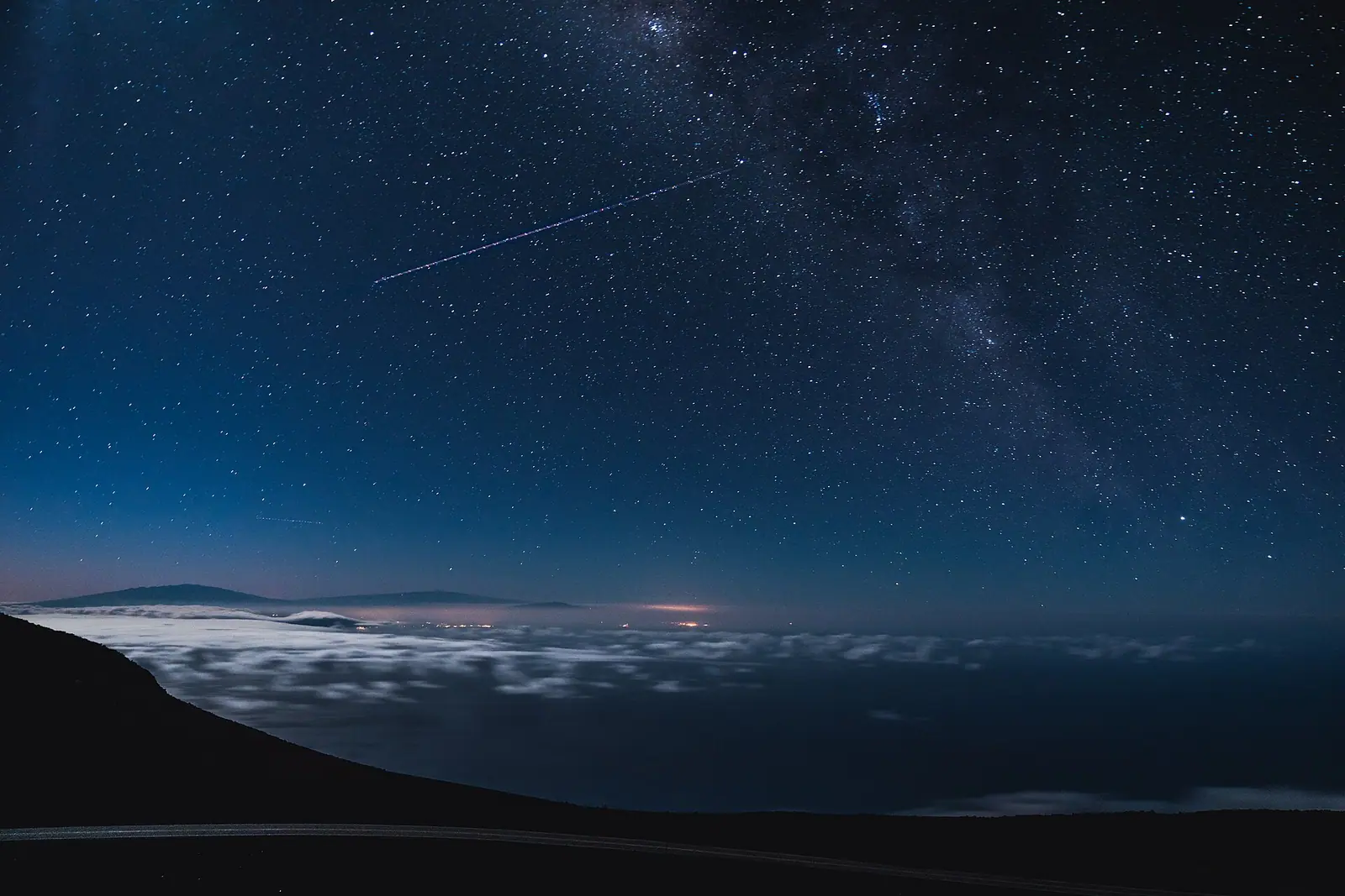 A mountain ridge standing above an unbroken layer of cloud at first light