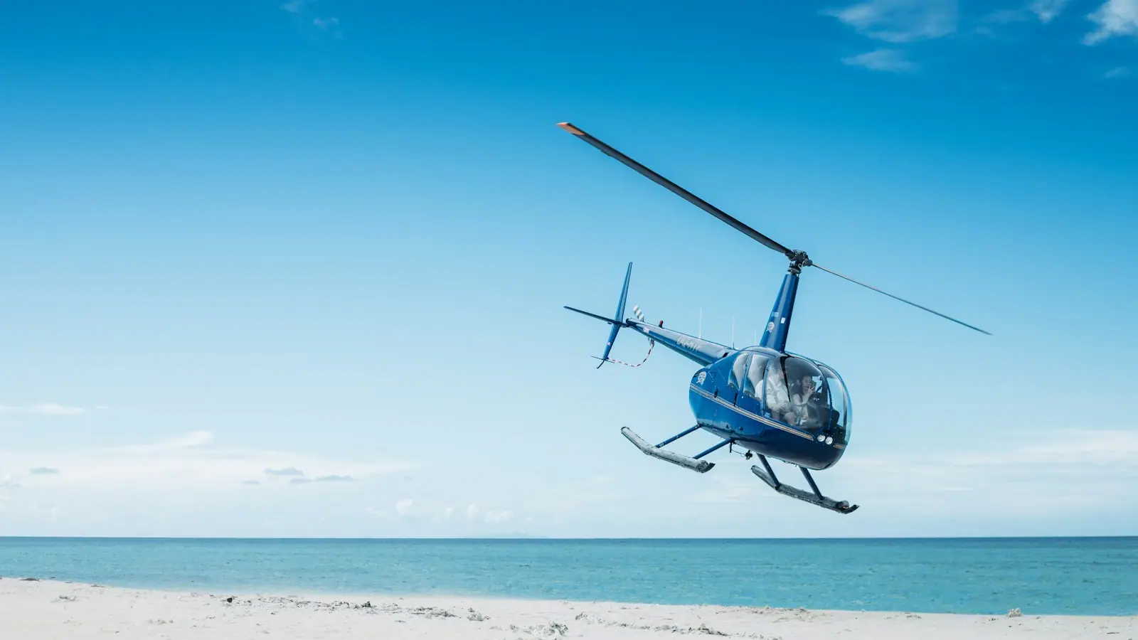 A tour helicopter in flight low over a coastline