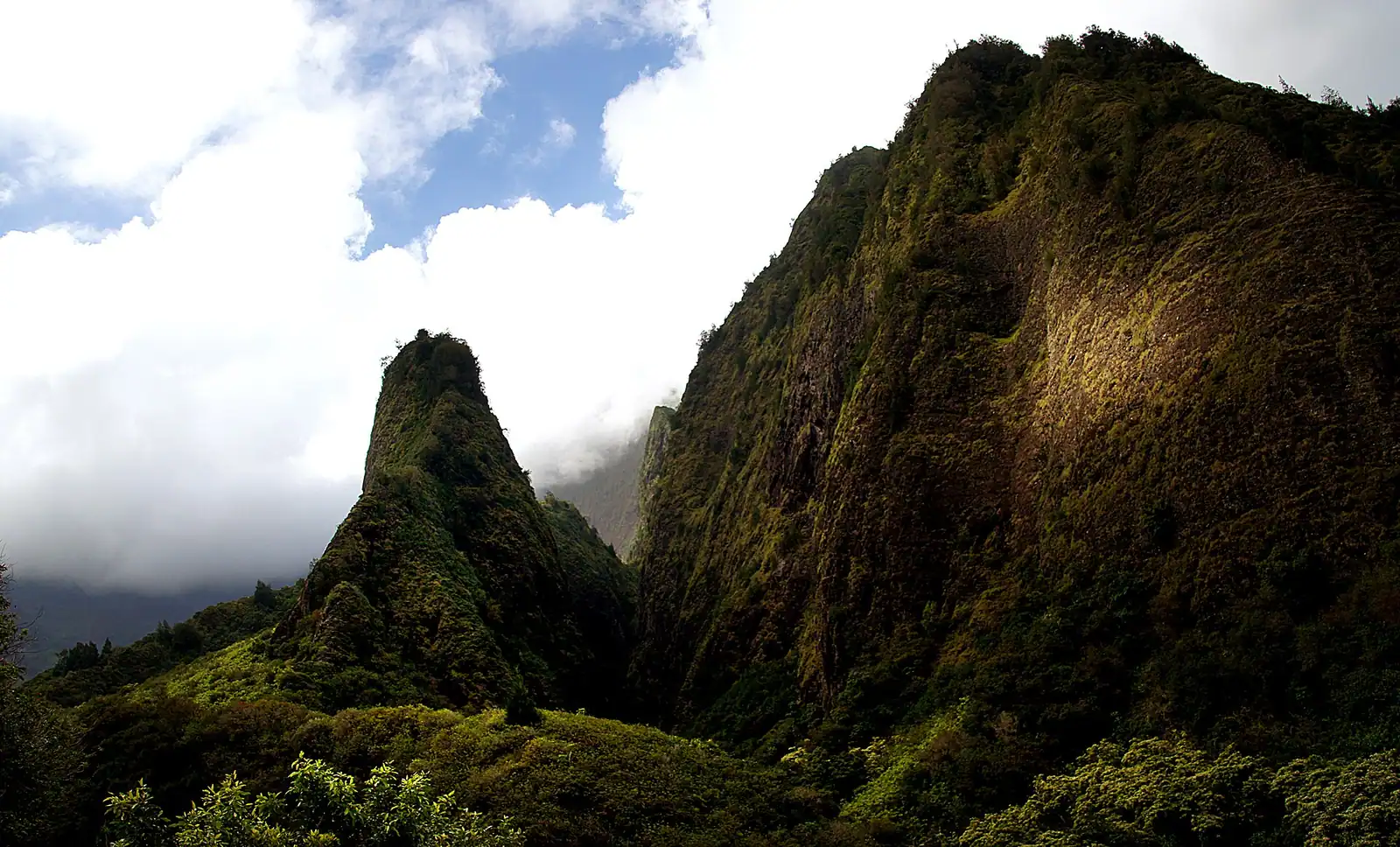 A sharp green ridge rising steeply out of a densely vegetated valley